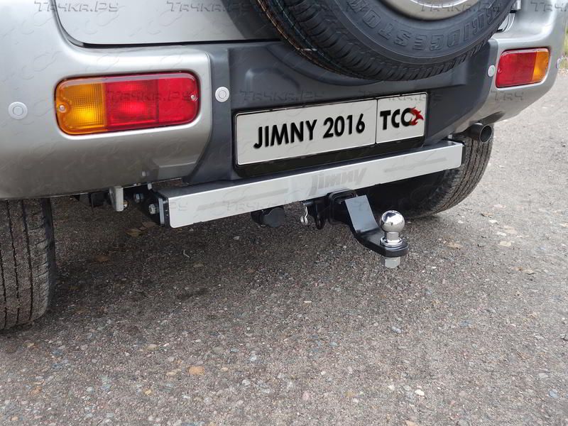 Фаркоп оцинкованный под американский квадрат ТСС для Suzuki Jimny 2012-2018 с накладкой с надписью Jimny . Артикул TCU00093