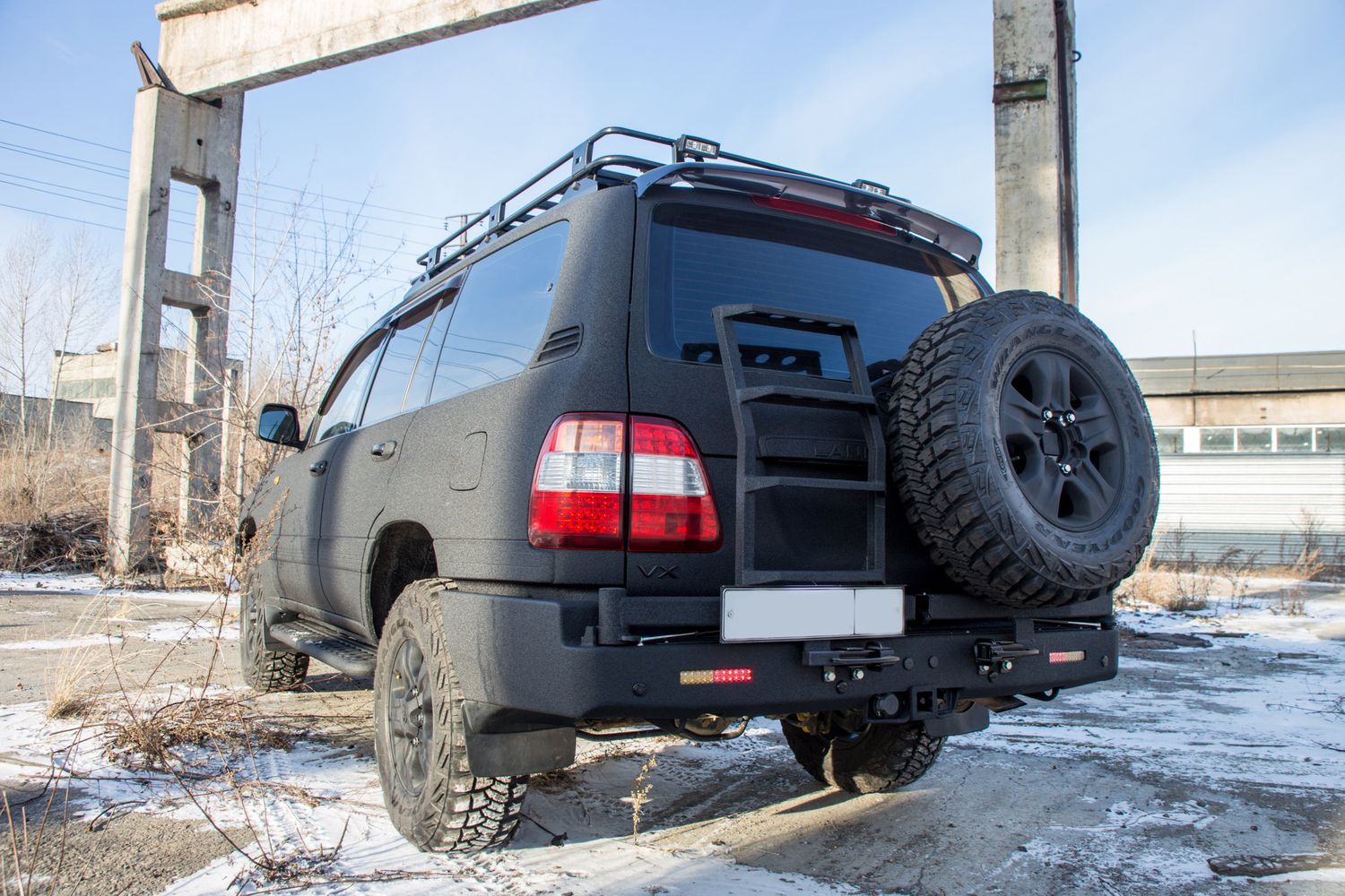 Бампер силовой задний STC для Toyota Land Cruiser 105 1998-2007 с квадратом под фаркоп,кронштейном крепления запасного колеса справа, кронштейн лестница слева и дублирующими фонарями. Артикул STC-TLC105-BR-C2C5-L1